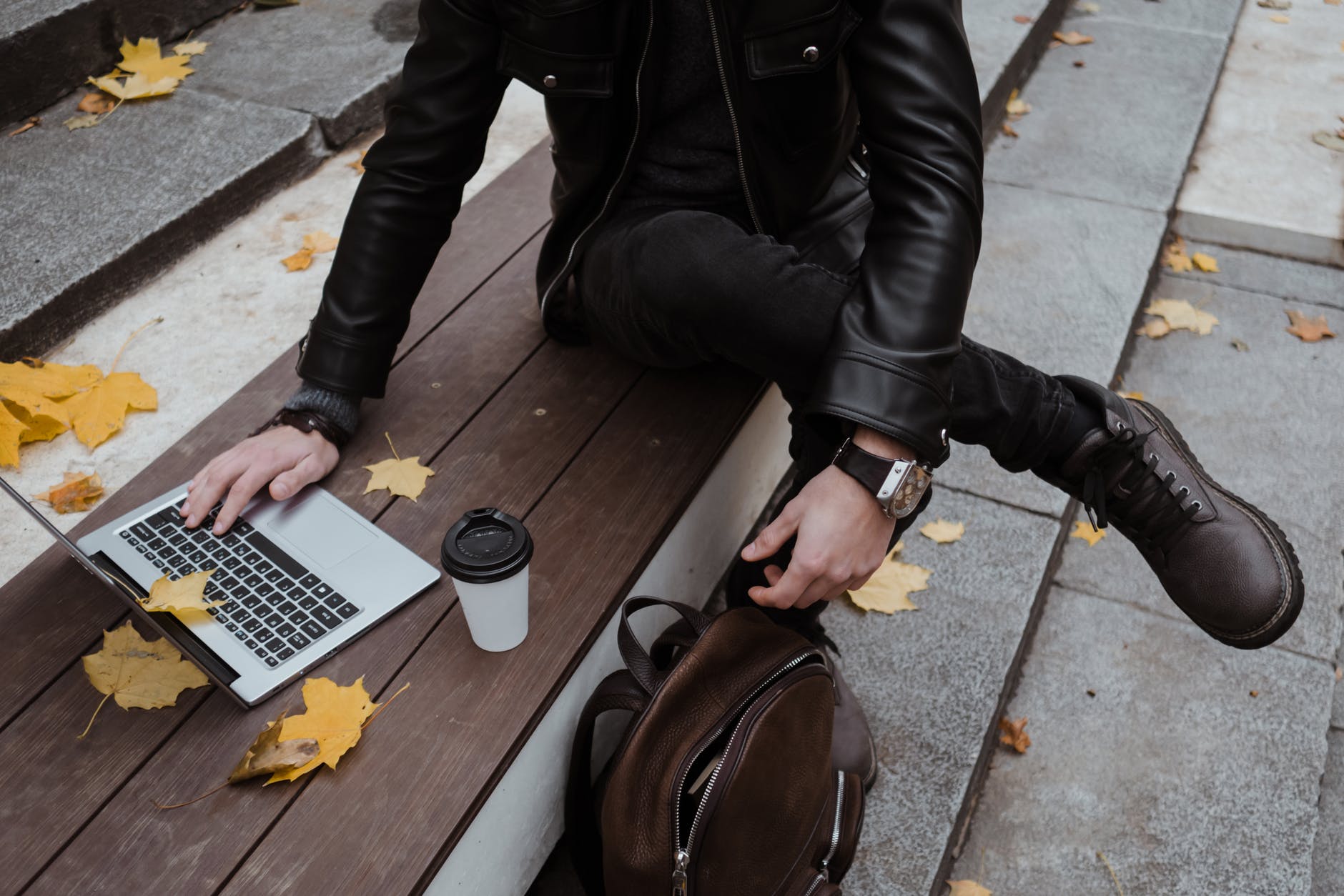 person in black leather jacket using a laptop